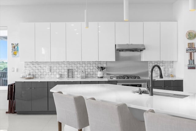 kitchen with a breakfast bar, decorative backsplash, white cabinetry, and sink