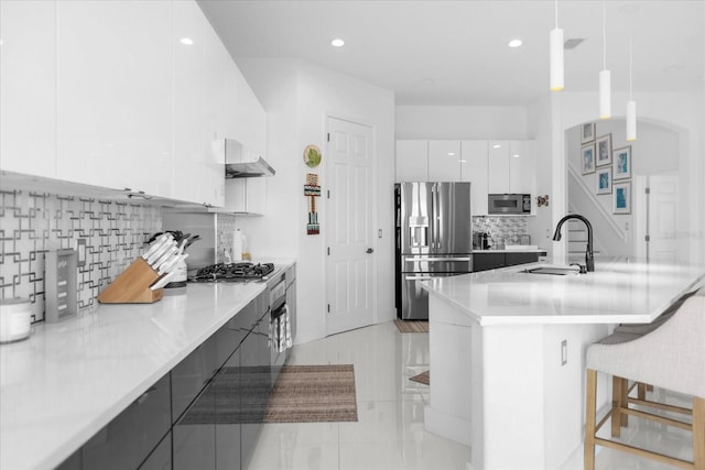 kitchen featuring sink, backsplash, pendant lighting, white cabinets, and appliances with stainless steel finishes