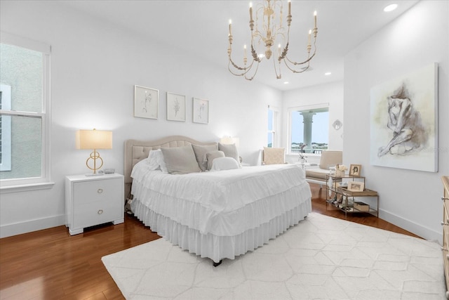 bedroom with multiple windows, an inviting chandelier, and hardwood / wood-style flooring