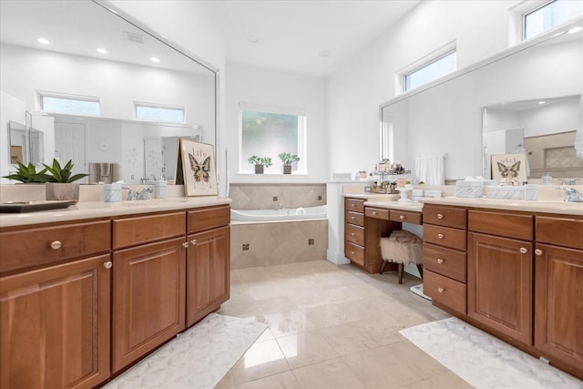 bathroom with vanity, a relaxing tiled tub, and tile patterned floors