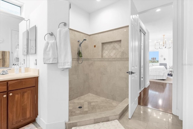 bathroom with a tile shower, vanity, an inviting chandelier, and tile patterned floors