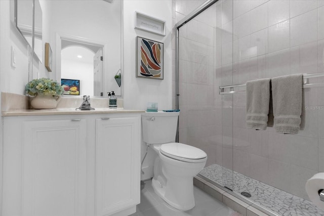 bathroom with tile patterned floors, a shower with door, vanity, and toilet