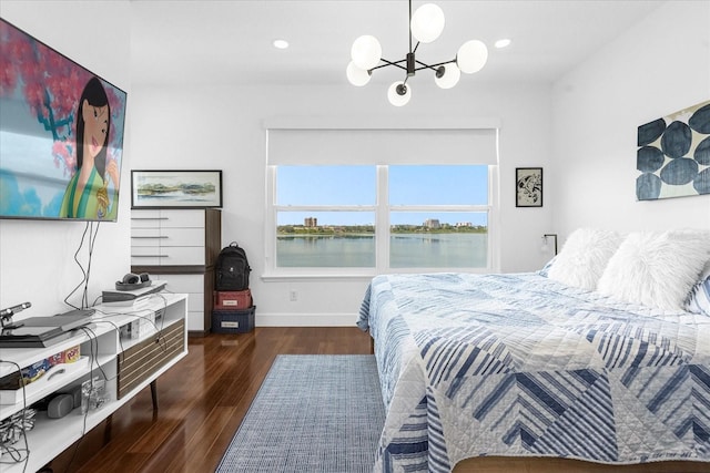 bedroom with a notable chandelier, a water view, and dark wood-type flooring