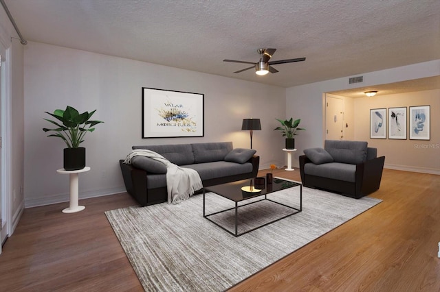 living room featuring ceiling fan, hardwood / wood-style floors, and a textured ceiling