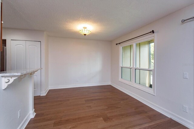 unfurnished dining area featuring a textured ceiling and dark hardwood / wood-style floors