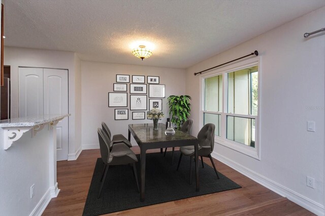 dining area with plenty of natural light, a textured ceiling, and dark hardwood / wood-style floors