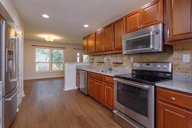 kitchen featuring decorative backsplash, sink, light stone counters, and stainless steel appliances