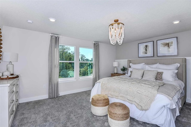 bedroom with dark colored carpet, a textured ceiling, and an inviting chandelier