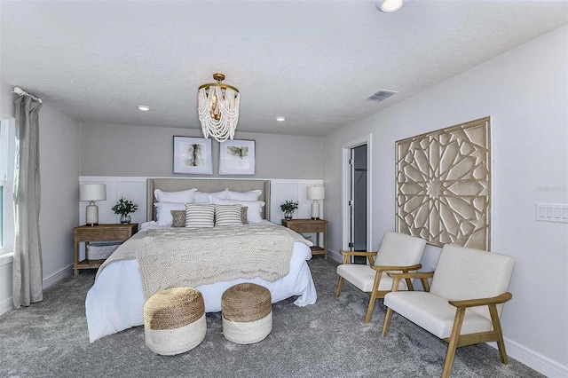 bedroom with dark colored carpet, a textured ceiling, and an inviting chandelier