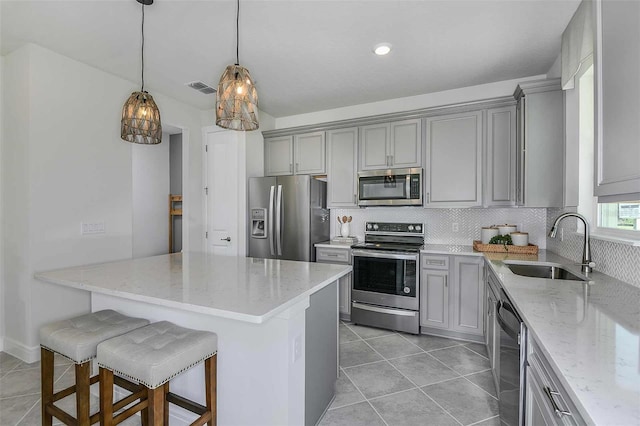 kitchen with a breakfast bar, appliances with stainless steel finishes, light stone countertops, and sink