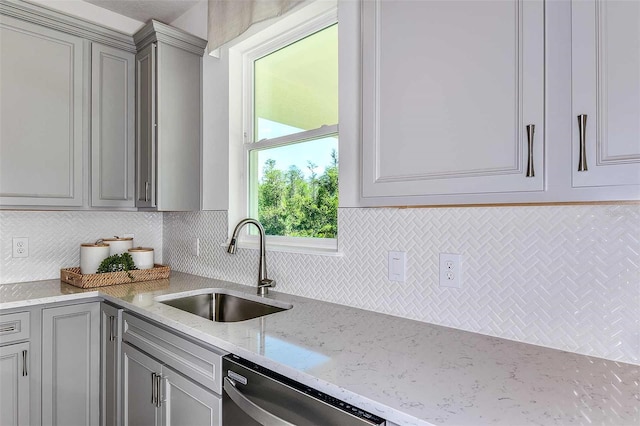 kitchen featuring sink, dishwasher, light stone counters, backsplash, and gray cabinets