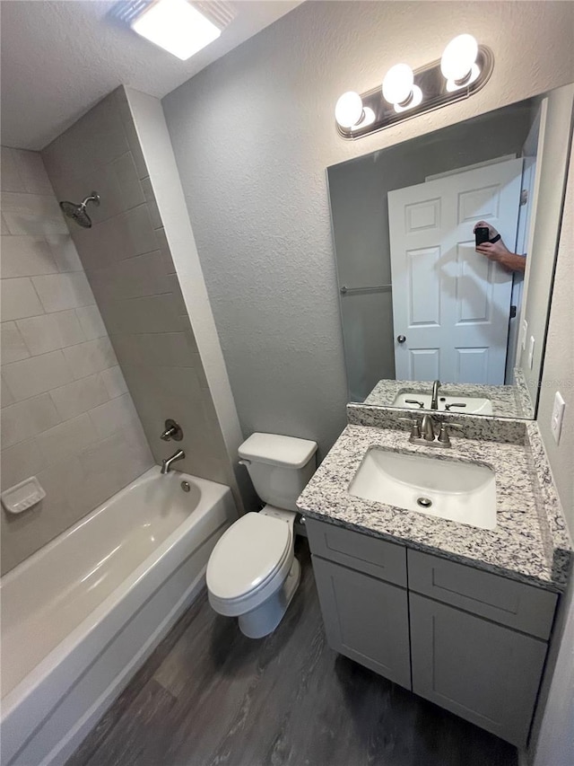 full bathroom with vanity, toilet, tiled shower / bath combo, and hardwood / wood-style floors