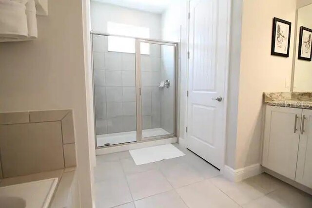 bathroom with a shower with shower door, vanity, and tile patterned flooring