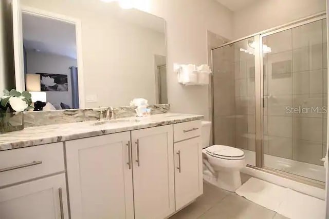 bathroom with tile patterned flooring, toilet, vanity, and an enclosed shower