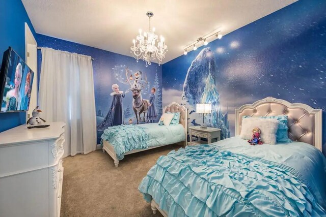 carpeted bedroom featuring rail lighting and a notable chandelier