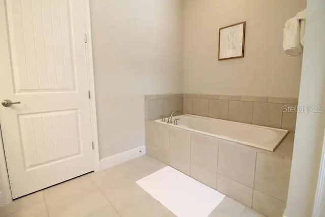 bathroom with a relaxing tiled tub and tile patterned floors