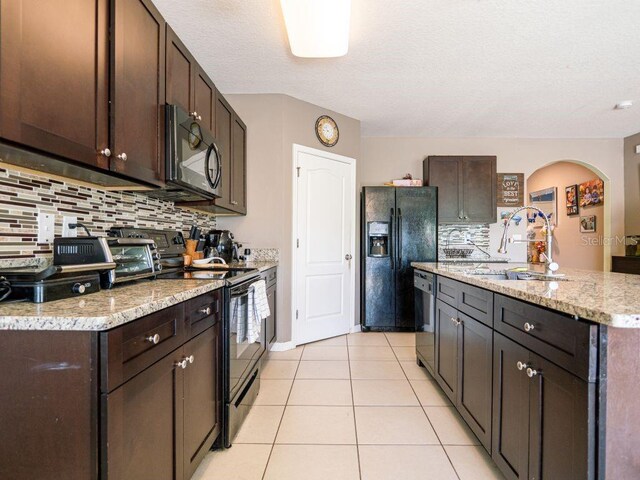 kitchen featuring dark brown cabinets, stainless steel appliances, backsplash, light tile floors, and sink