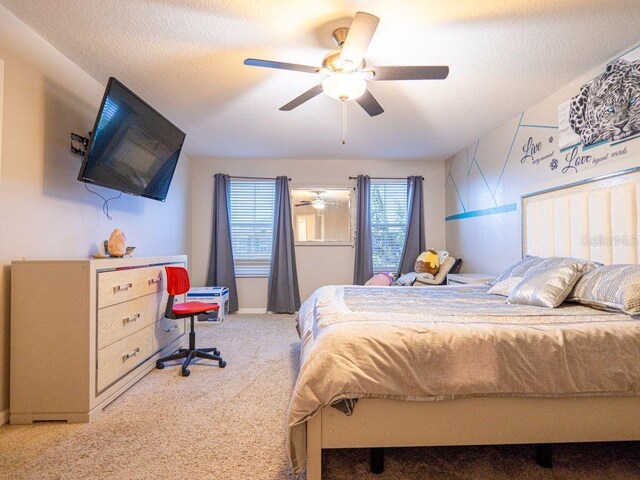 carpeted bedroom featuring ceiling fan and a textured ceiling