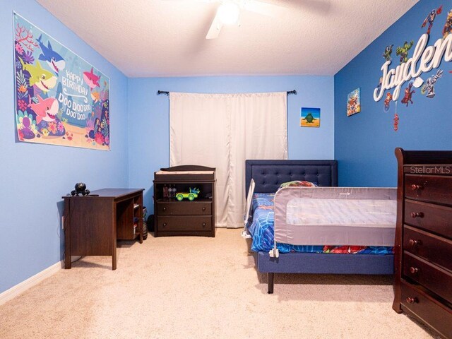 carpeted bedroom featuring ceiling fan and a textured ceiling