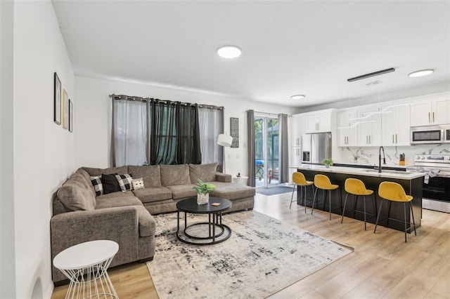 living room featuring sink and light hardwood / wood-style floors