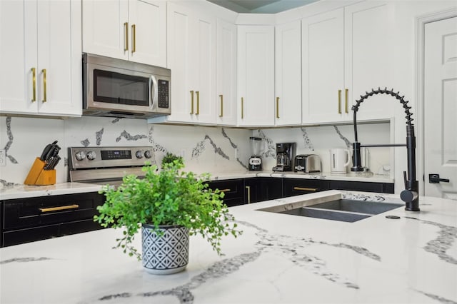 kitchen featuring white cabinetry, stainless steel appliances, light stone countertops, and decorative backsplash