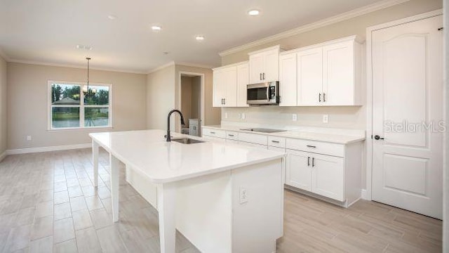 kitchen featuring a center island with sink, pendant lighting, white cabinetry, and sink