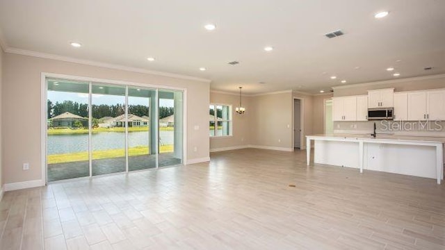 unfurnished living room featuring an inviting chandelier, crown molding, and light hardwood / wood-style flooring