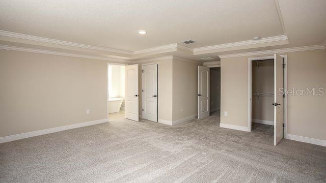 unfurnished bedroom with light carpet, ensuite bath, crown molding, and a tray ceiling