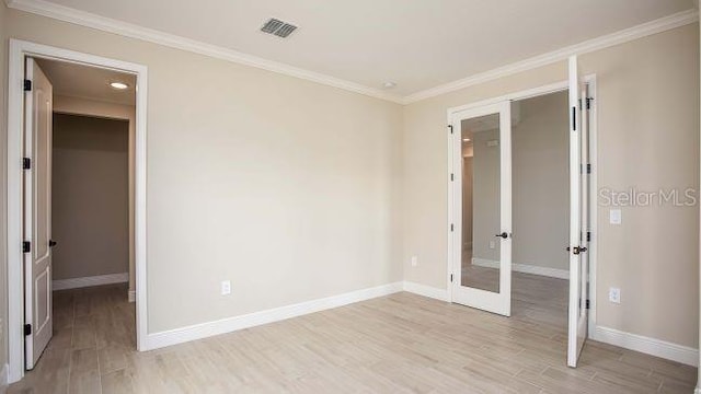 unfurnished bedroom featuring french doors, crown molding, and light wood-type flooring