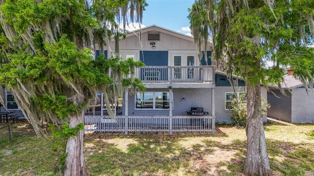 back of house featuring a lawn and a balcony