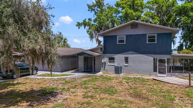 rear view of house featuring a lawn and central air condition unit