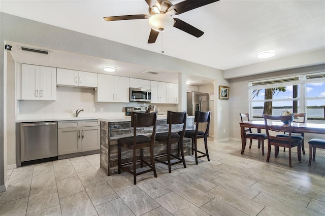 kitchen featuring ceiling fan, light tile floors, sink, white cabinetry, and appliances with stainless steel finishes