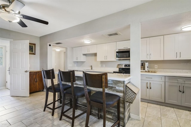 kitchen featuring ceiling fan, stainless steel appliances, light tile flooring, gray cabinetry, and white cabinets