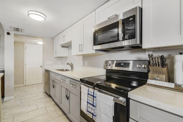1149 Shady Cove Rd E, Haines City, FL 33844 - kitchen with appliances with stainless steel finishes, a sink, baseboards, and white cabinets