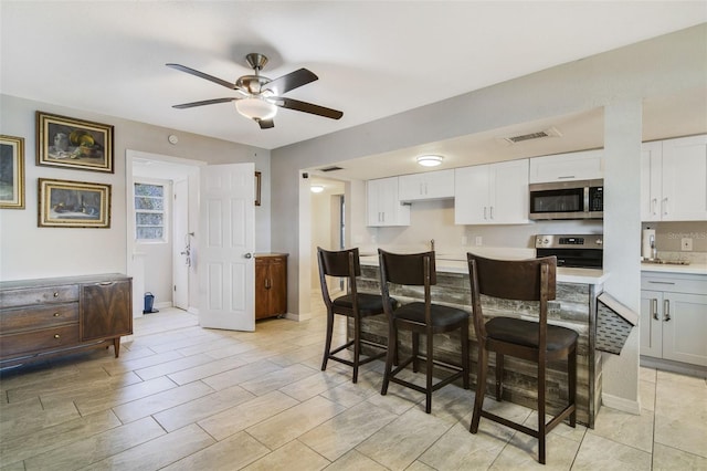 kitchen with ceiling fan, white cabinets, light tile floors, and stove