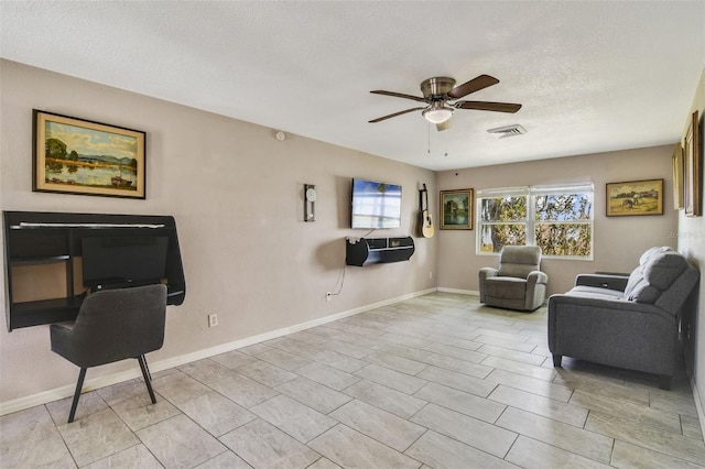 living room with ceiling fan, a textured ceiling, and light tile floors