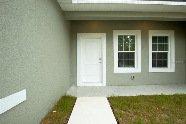 entrance to property featuring stucco siding