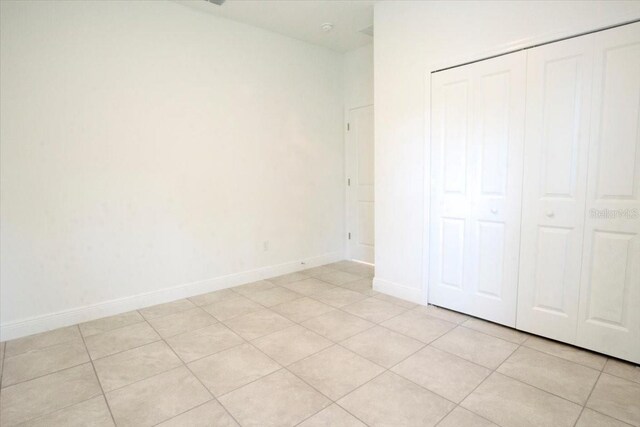 unfurnished bedroom featuring light tile patterned floors, a closet, and baseboards