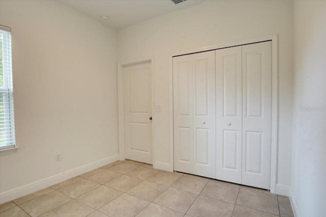 unfurnished bedroom featuring light tile patterned flooring and a closet