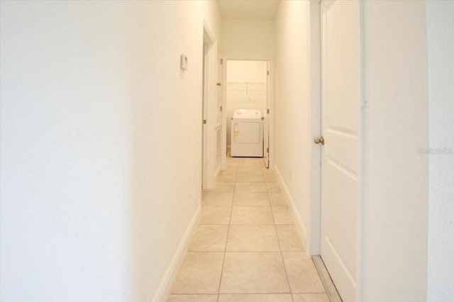 corridor with light tile patterned floors, baseboards, and washer / clothes dryer