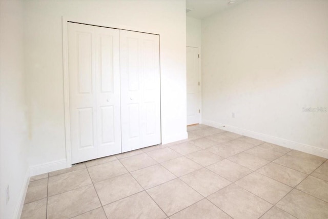 unfurnished bedroom featuring light tile patterned floors, baseboards, and a closet