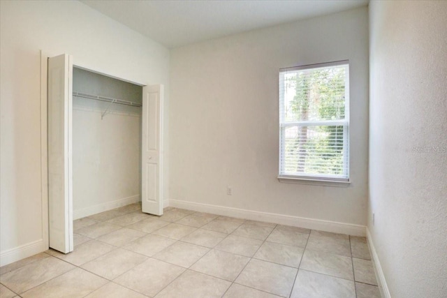 unfurnished bedroom featuring a closet, baseboards, and light tile patterned flooring