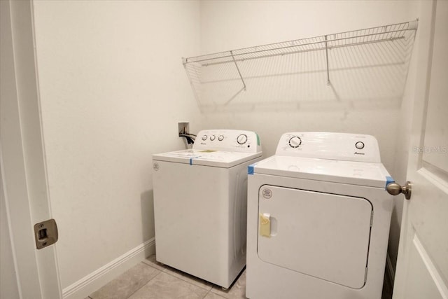 washroom featuring baseboards, separate washer and dryer, light tile patterned flooring, and laundry area