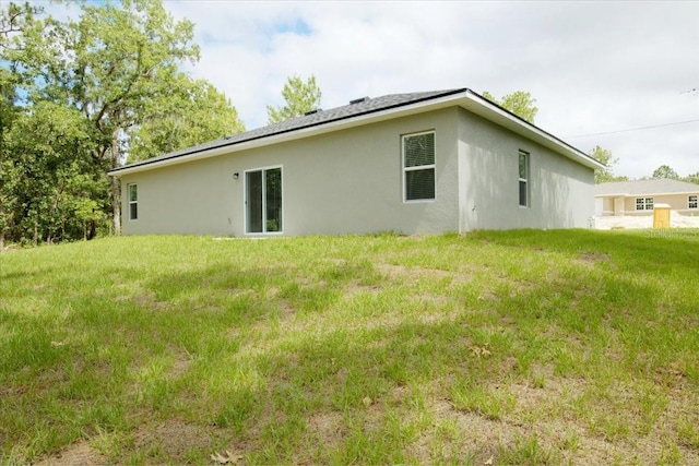 rear view of property with stucco siding and a lawn