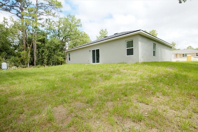 back of property featuring stucco siding and a yard