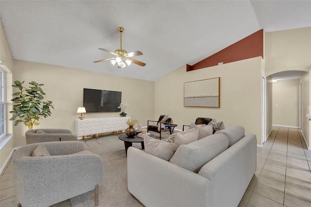 living room featuring ceiling fan, vaulted ceiling, a textured ceiling, and light tile patterned floors