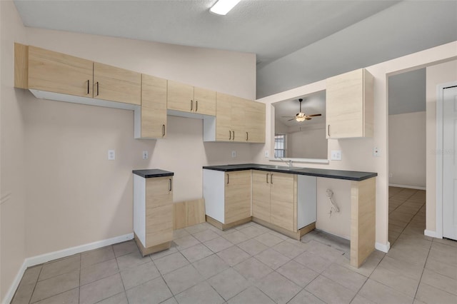 kitchen featuring vaulted ceiling, sink, light tile patterned floors, and light brown cabinetry