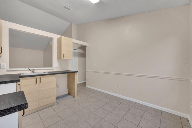 2519 Woods Edge Cir, Orlando, FL 32817 - kitchen with light brown cabinetry, a sink, dark countertops, vaulted ceiling, and visible vents