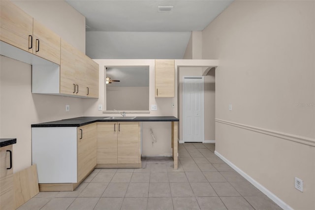 2519 Woods Edge Cir, Orlando, FL 32817 - kitchen with dark countertops, light brown cabinetry, a sink, and light tile patterned floors