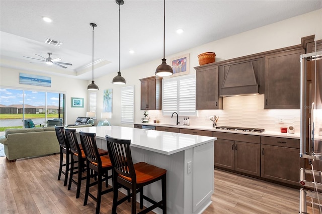 kitchen with appliances with stainless steel finishes, premium range hood, ceiling fan, pendant lighting, and a kitchen island